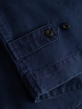 Close-up of the BGlumen Nebraska Gilet in blue by Blue de Gênes, featuring a flap pocket secured with two black buttons and detailed visible stitching. The high-density cotton fabric showcases its textured durability and classic workwear-inspired style.