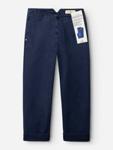 The BGliam Nebraska Chino - Blue from Blue de Gênes features a straight-leg silhouette in navy blue, crafted from high-density dobby weave cotton for enhanced durability and texture. Designed with a button and zipper front, these chinos include turned-up cuffs and a white tag attached to a belt loop that displays product information along with an image of the pants.