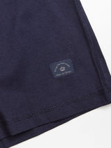 Close-up of the dark navy fabric of the Sagi Nuovo T-shirt by Blue de Gênes, featuring precise stitching and a small rectangular sewn-on label near the hem that reads Blue de Gênes—showcasing the meticulous craftsmanship that makes this piece an essential men’s wardrobe staple.