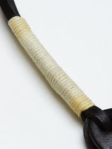 Close-up of the BGsavino Key Hanger - Black by Blue de Gênes, featuring a black leather strap with cream-colored string tightly wrapped around its center, placed on a white background.