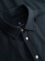 Close-up of the BGenrico Tessusto Shirt in navy, a men’s casual shirt by Blue de Gênes, featuring a dark honeycomb textured button-up design with a collar, three white buttons, and an inner label displaying the Blue de Gênes name and signature cross logo.