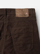 Close-up of the back pocket and waistband of the BGpaulo Ottawa V3 Trousers in Hot Fudge Brown by Blue de Gênes, highlighting a leather patch with Blue de Gênes branding and a small Swiss flag emblem. The textured dobby corduroy fabric is clearly visible, showcasing the trousers’ regular slim fit design.