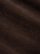Close-up of hot fudge brown corduroy fabric with pronounced ridges and a soft texture, revealing the intricate wavy patterns and fine details typical of our BGpaulo Ottawa V3 Trousers by Blue de Gênes—regular slim fit pants inspired by the classic Paulo Ottawa Chino.