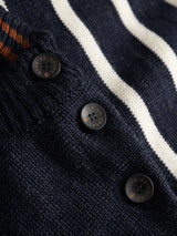 Close-up of a BGdaw Stripe Knit - Navy 100% wool crewneck sweater in navy blue with white and orange stripes and three dark buttons engraved with text.