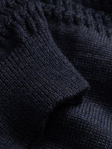 Close-up of a navy blue BGstu Rollneck Knit sweater featuring a textured knit, ribbed cuff, and a roll-neck.