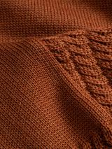 Close-up of a rust-orange Blue de Gênes BGstu Rollneck Knit - Ginger Bread Orange, featuring a 100% wool roll-neck design with a combination of smooth stockinette stitch and vertical cable knit patterns.