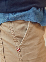 Close-up of Blue de Gênes BGpaulo Pavia V3 Chino in khaki, featuring a slanted front pocket and a small shield-shaped logo pin on the enzyme-washed cotton stretch fabric.
