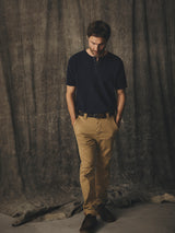 A man wearing a navy henley shirt and enzyme-washed BGpaulo Pavia V3 Chino - Khaki pants with his hands in his pockets.