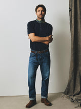 A man wearing a navy short-sleeved henley, a patterned neck scarf, and cuffed BGmarco Sioux Jeans - Used with a brown belt and boots.