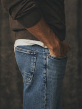 Side view of a person wearing Blue de Gênes BGvinci Pala Used V3 Jeans in denim blue, with a hand in the pocket.