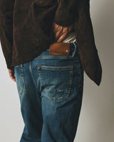 Person wearing BGvinci Girisha Used Jeans in a regular fit, five-pocket style with a brown leather patch on the back waistband.