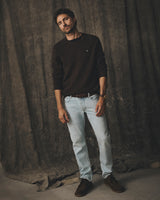 A man standing in a dark sweater and mid blue denim BGvinci Trueblue Jeans.