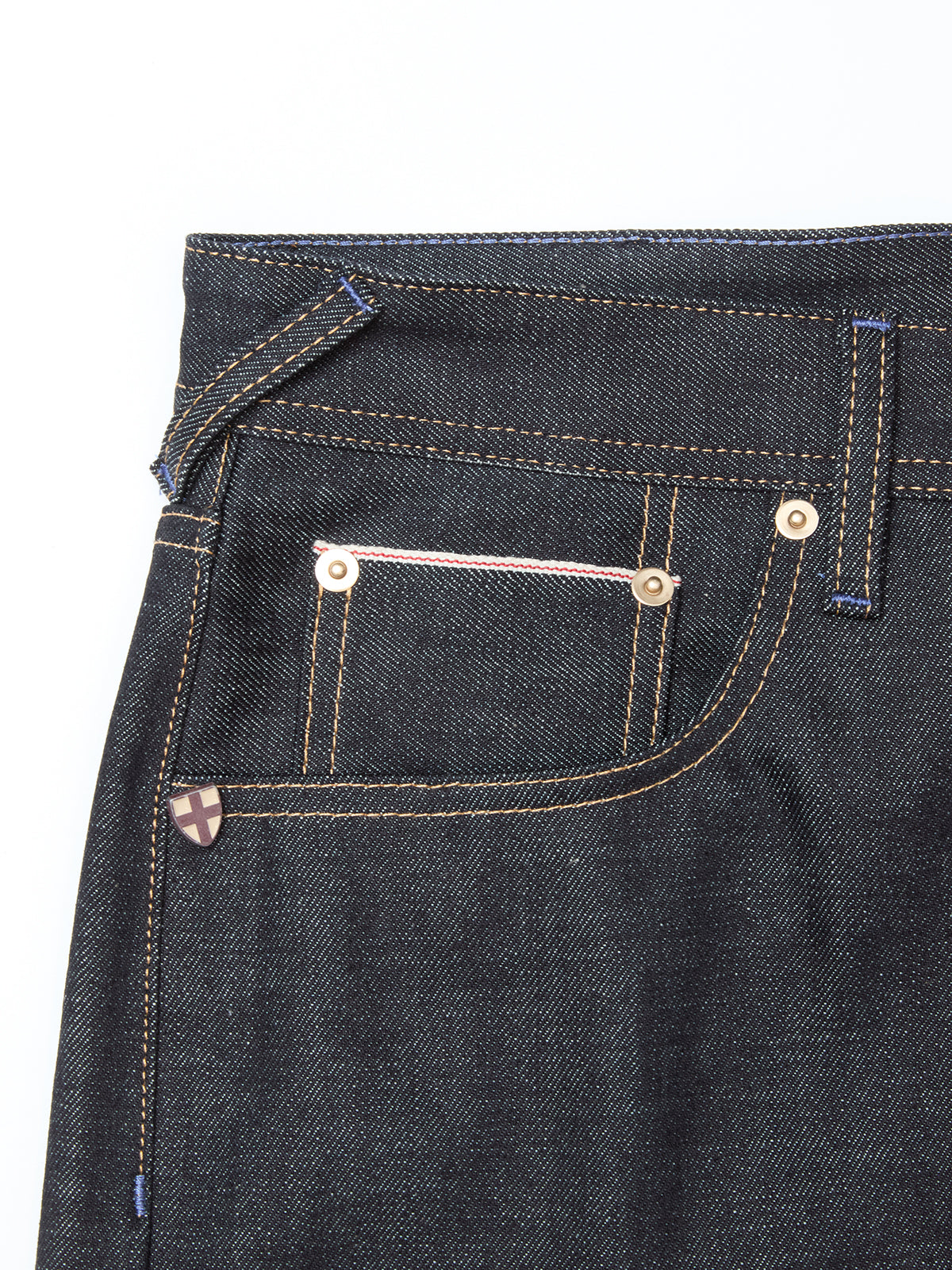 Close-up of the Giacomo Selvedge V2 Jeans by Blue de Gênes, featuring rigid raw denim, front and coin pockets with white and pink stitching, bronze rivets, a visible belt loop, and contrasting yellow stitching.