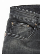 Close-up of the front pocket on Vinci G Dark Grey Jeans by Blue de Gênes, featuring a small coin pocket, copper rivets, and a fabric tag with a white cross on red near the seam, all crafted from comfort stretch grey denim.