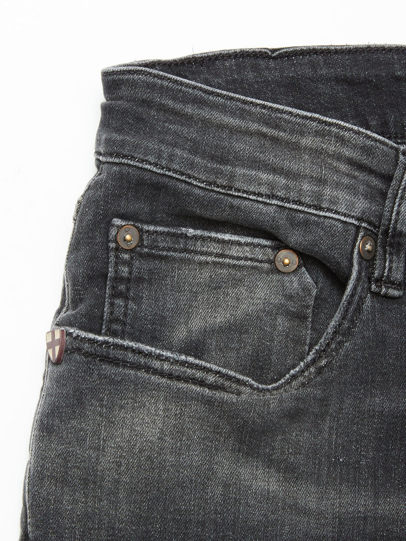 Close-up of the front pocket on Vinci G Dark Grey Jeans by Blue de Gênes, featuring a small coin pocket, copper rivets, and a fabric tag with a white cross on red near the seam, all crafted from comfort stretch grey denim.