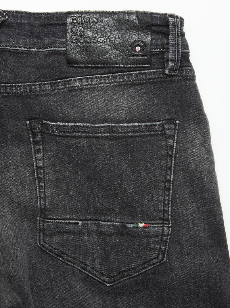 Close-up of the back pocket on Blue de Gênes Vinci G Dark Grey Jeans in grey denim, featuring a leather patch with embossed text and a small stitched red, white, and green detail near the edge—crafted in Italy.
