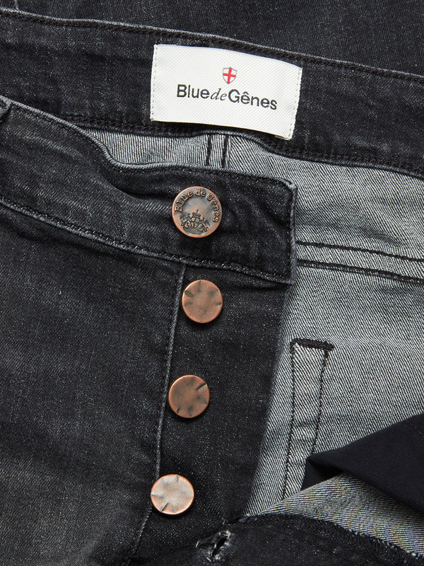 Close-up of Blue de Gênes Vinci G Dark Grey Jeans in grey denim, featuring comfort stretch, regular fit, a partially open button fly with copper buttons, and a white brand label sewn onto the waistband.