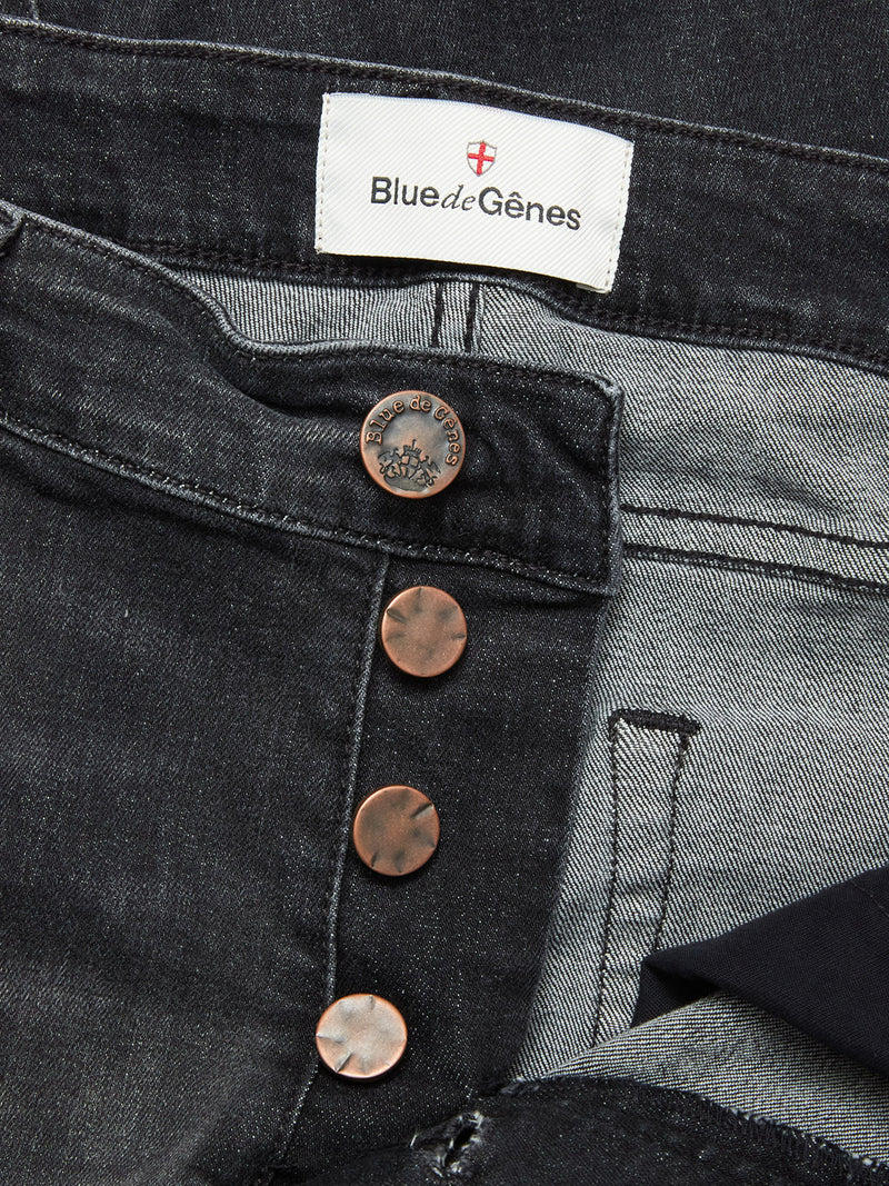 Close-up of Blue de Gênes Vinci G Dark Grey Jeans in grey denim, featuring comfort stretch, regular fit, a partially open button fly with copper buttons, and a white brand label sewn onto the waistband.