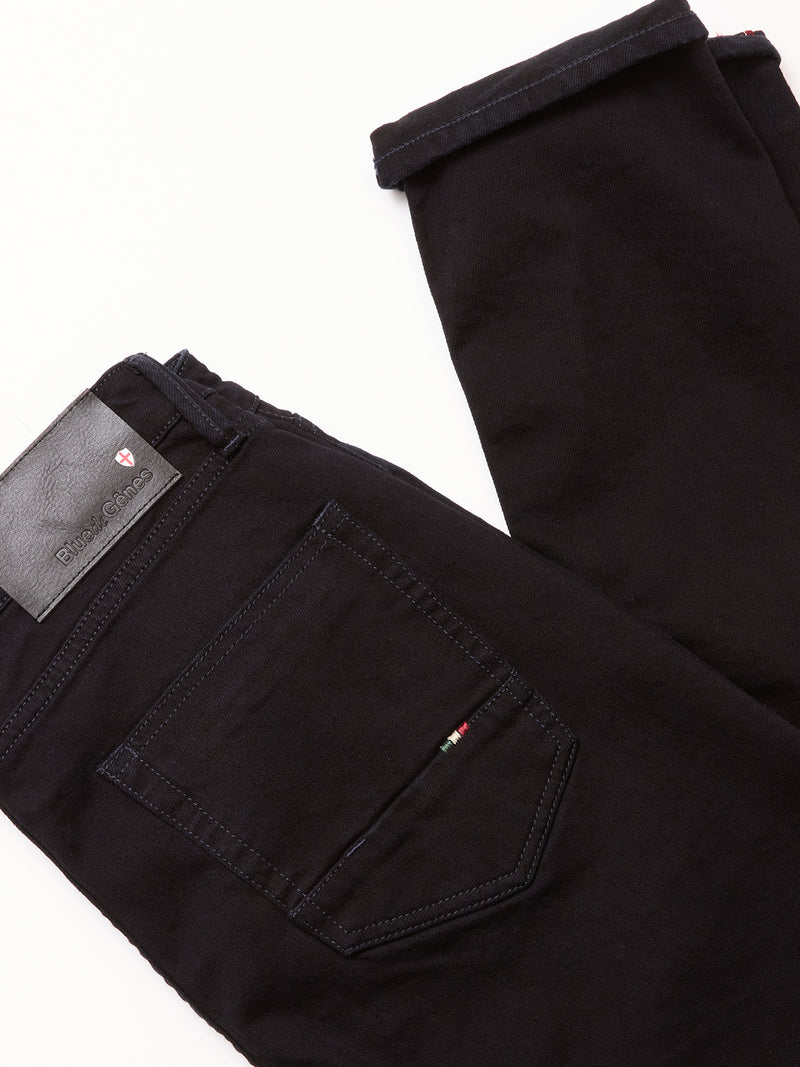 The Vinci Venom Blk Jeans - Dark Denim by Blue de Gênes are black regular fit jeans in comfort stretch denim, folded to display the back pocket, stitching details, and a black leather brand patch on the waistband.