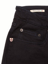 Close-up of the upper section of Blue de Gênes Vinci Venom Blk Jeans - Dark Denim, showing a small front pocket, metal rivet, pink and white cross emblem, and a Made in Italy label with flag. Crafted from comfort stretch twill for ease.
