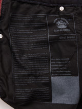 Close-up of Vinci Venom Blk Jeans by Blue de Gênes, showing a printed label inside with the logo, brand name, and text about Leonardo da Vinci’s inspiration. White text stands out on dark comfort stretch denim.