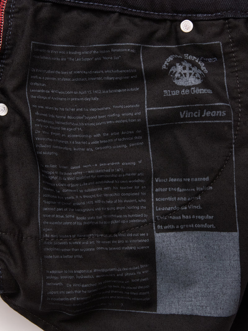 Close-up of Vinci Venom Blk Jeans by Blue de Gênes, showing a printed label inside with the logo, brand name, and text about Leonardo da Vinci’s inspiration. White text stands out on dark comfort stretch denim.