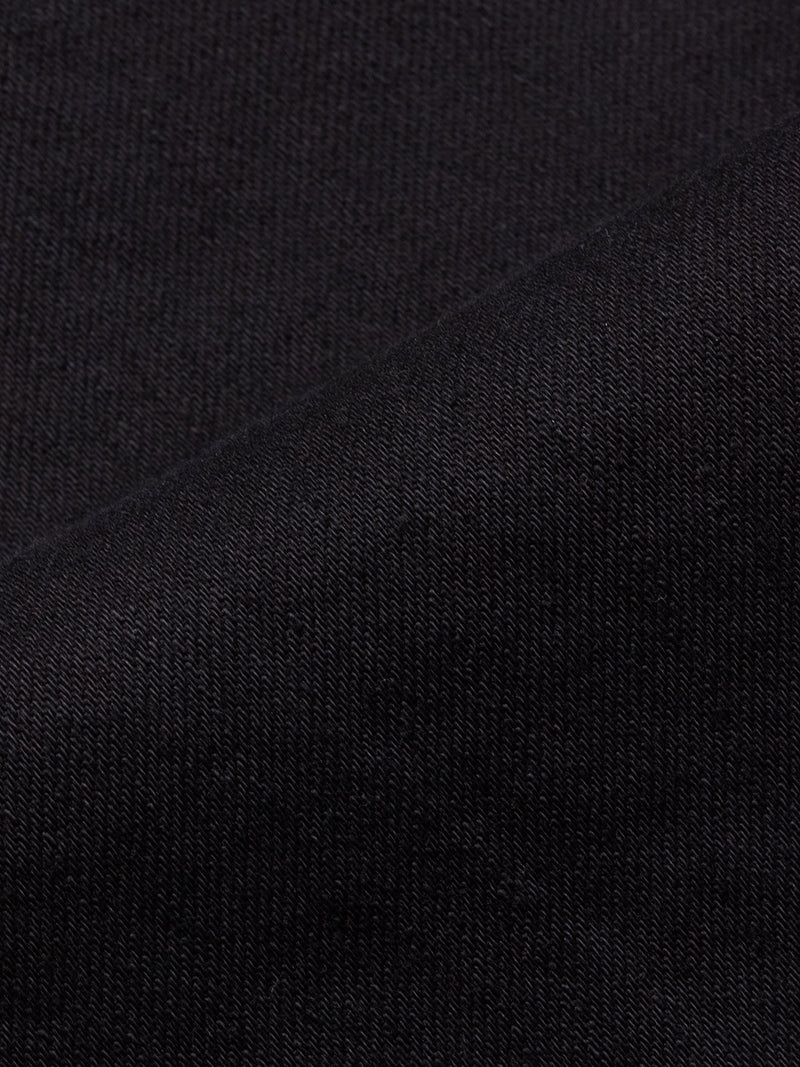 Close-up of Blue de Gênes Vinci Venom Blk Jeans in dark denim shows the comfort stretch fabric’s textured knit and fine weave, with a diagonal seam for added detail and a soft, slightly stretchy appearance.