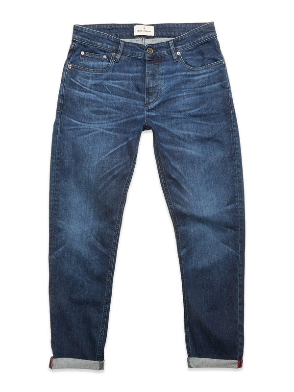 The Vinci Used Jeans - Used by Blue de Gênes are blue regular fit jeans with a classic five-pocket design, cuffed hems, and subtle fading and whiskering. Made from comfort stretch denim, they are shown laid flat on a white background.