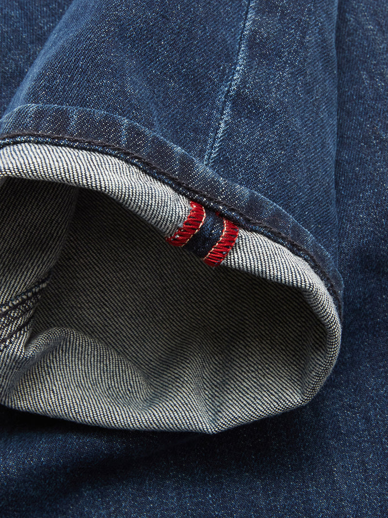 A close-up of the cuff on Vinci Used Jeans - Used by Blue de Gênes, regular fit and made in Italy from dark blue selvedge denim, featuring a visible white edge and red stitching detail.