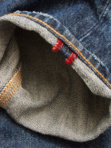 Close-up of the inside hem on Blue de Gênes Giacomo Osaka Jeans in dark denim, showing a white-blue striped selvedge with dual red stitches and an orange seam. Made in Italy.