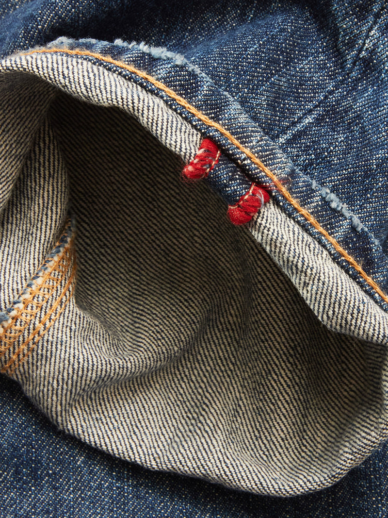 Close-up of the inside hem on Blue de Gênes Giacomo Osaka Jeans in dark denim, showing a white-blue striped selvedge with dual red stitches and an orange seam. Made in Italy.