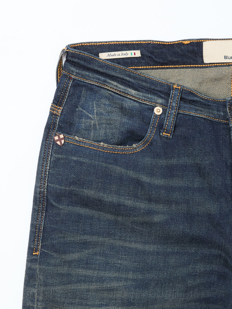 A close-up of the upper part of Blue de Gênes Repi Dark Vintage Jeans in mid blue denim shows the front pocket, belt loops, a metal accent, and an inside label with “Made in Italy” and an Italian flag.