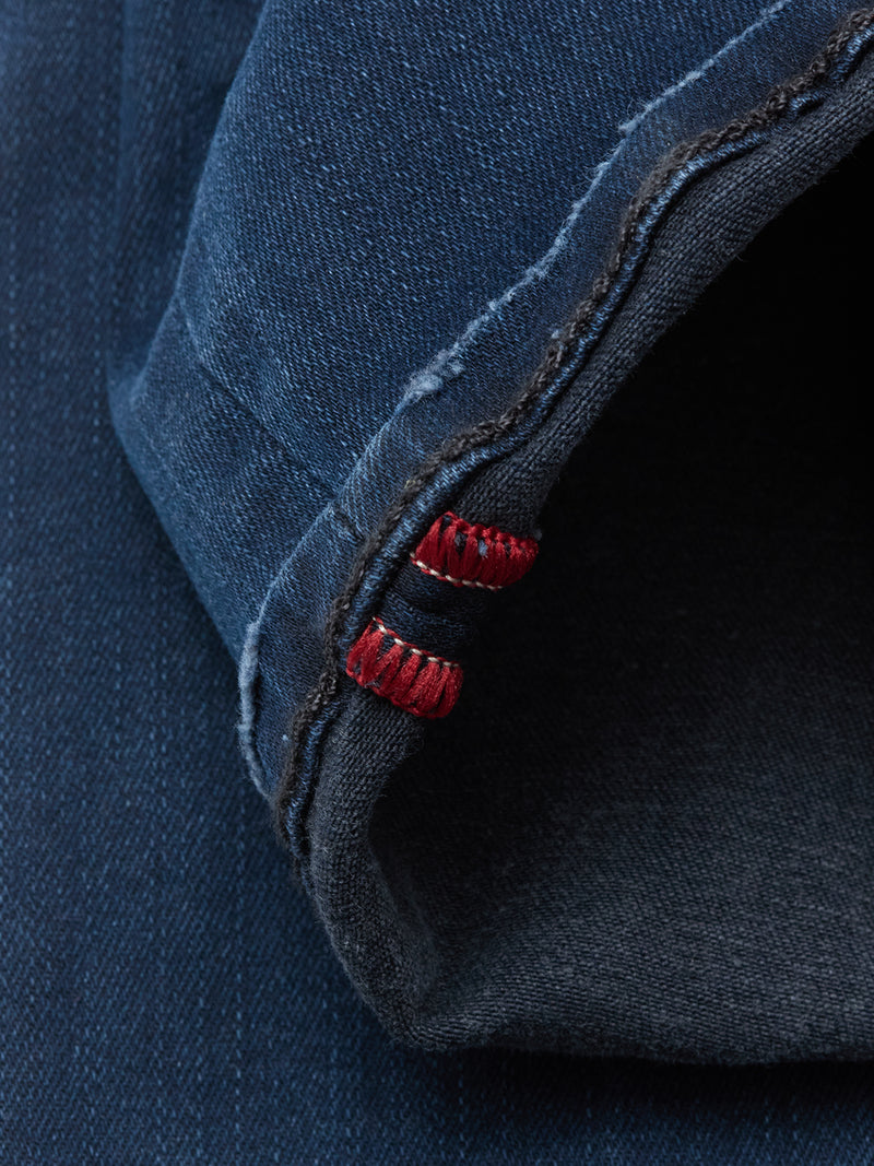 Close-up of a rolled cuff on Blue de Gênes Repi BlueBlk Used Jeans in blue black denim, showing the inside seam with red stitching detail.