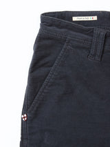 Close-up of Blue de Gênes BGpaulo Ottawa Trousers in dark navy dobby corduroy, showing the front pocket, belt loop, an embroidered shield emblem by the pocket, and a small "Made in Italy" label near the waistband.