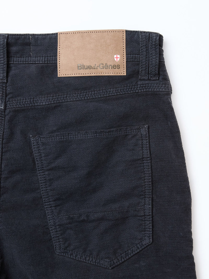 Close-up of the back of BGpaulo Ottawa Trousers in dark navy by Blue de Gênes, featuring a single back pocket and a tan leather patch with the brand name and red and white shield logo, made in Italy.