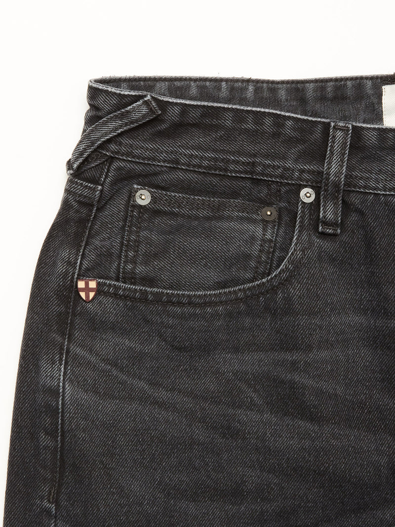Close-up of the upper part of Blue de Gênes Giacomo BLK Used Jeans in grey denim, made in Italy, featuring a relaxed loose fit, waistband, belt loop, front pocket, and a small badge with a red and white cross near the pocket.