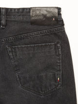 Close-up of the back pocket of Giacomo BLK Used Jeans in grey denim by Blue de Gênes, featuring a small Italian flag tag and a black leather patch on the waistband embossed with the brand name, highlighting quality made in Italy.