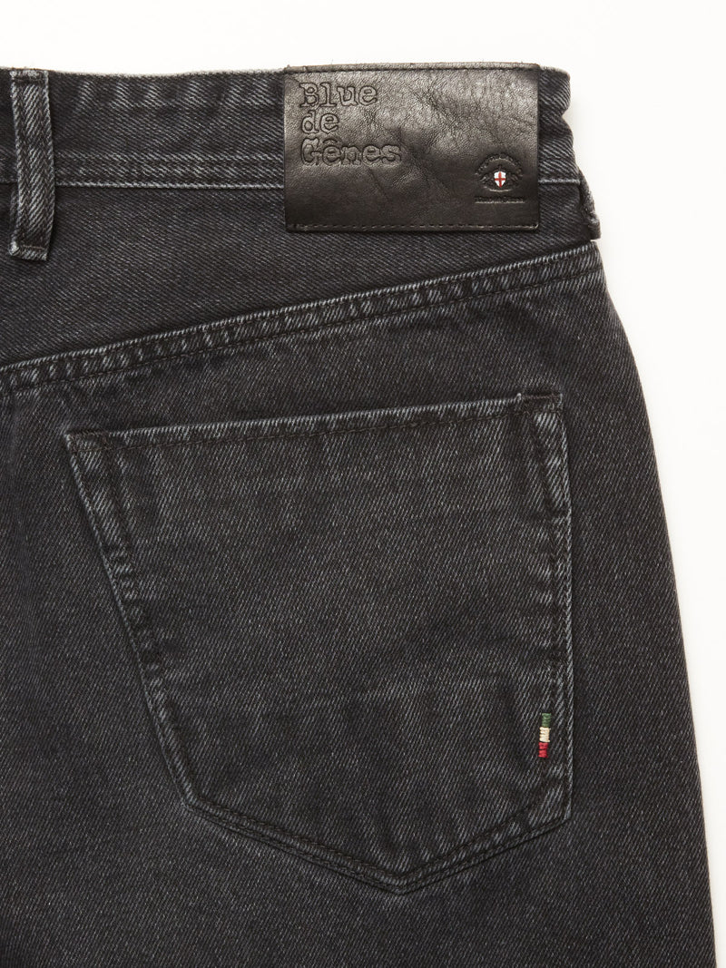 Close-up of the back pocket of Giacomo BLK Used Jeans in grey denim by Blue de Gênes, featuring a small Italian flag tag and a black leather patch on the waistband embossed with the brand name, highlighting quality made in Italy.