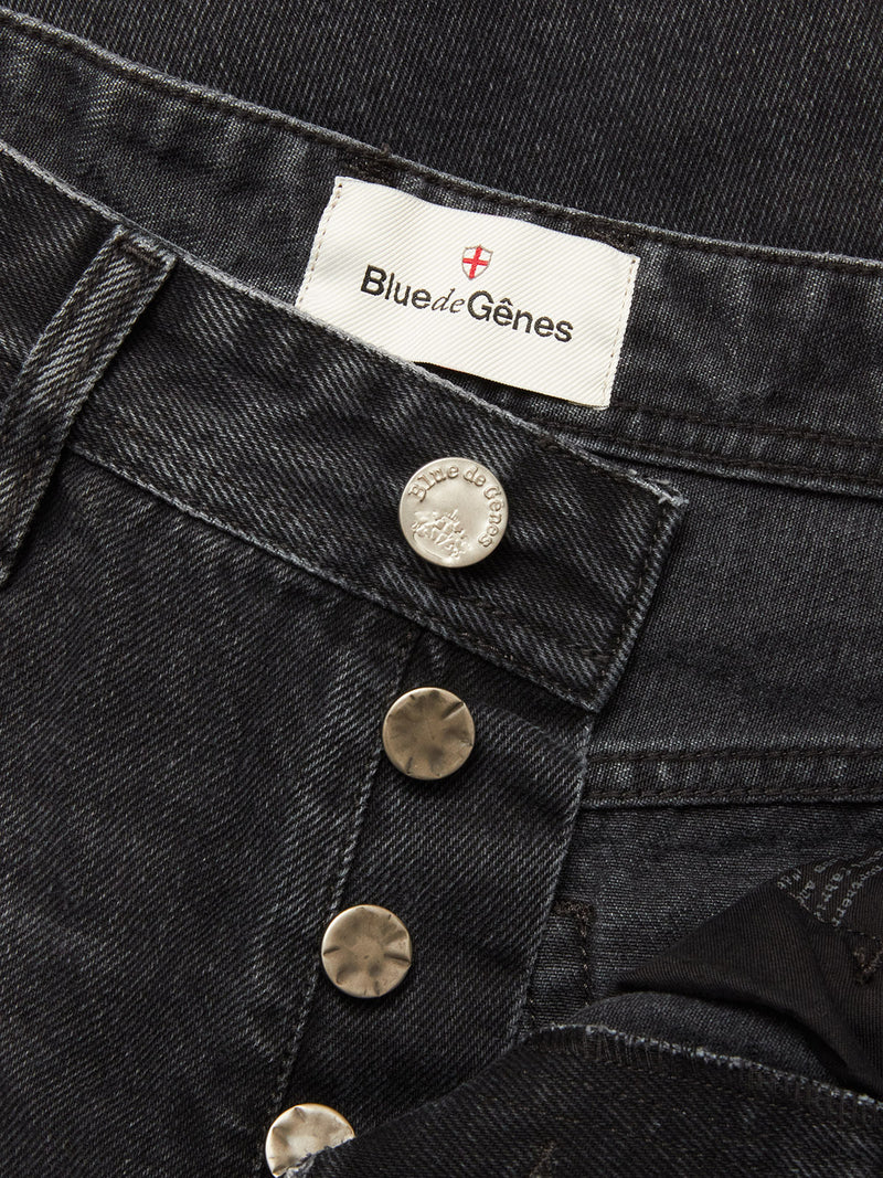 Close-up of Blue de Gênes Giacomo BLK Used Jeans in grey denim with metallic buttons undone, revealing a white label inside the waistband. These rigid denim jeans offer a relaxed loose fit for timeless style and comfort.