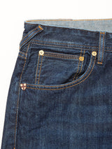 Close-up of the front pocket on Blue de Gênes Giacomo Dark Horse Jeans in denim blue, highlighting golden stitching, metal rivets, and a red cross shield patch—signature details of these relaxed loose fit jeans made in Italy.