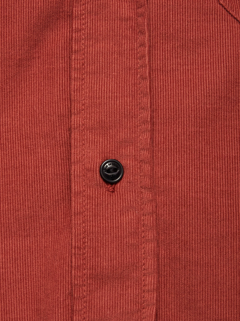 Close-up of the Zamboni Velu Shirt - Henna by Blue de Gênes: red baby corduroy with vertical ridges and a black button on the placket, showcasing classic garment-dyed detailing inspired by Blue de Gênes craftsmanship.
