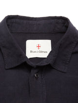 A close-up of the Zamboni Velu Shirt in navy baby corduroy, featuring a Blue de Gênes label inside the collar beneath a red and white shield emblem.