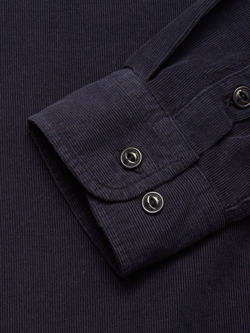 Close-up of the Blue de Gênes Zamboni Velu Shirt - Navy cuff, featuring two black buttons and showcasing its textured, ribbed baby corduroy fabric in a deep garment-dyed navy shade.