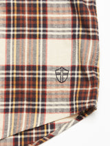 A close-up of the Robertino Brush Shirt - Stone by Blue de Gênes, showcasing plaid fabric in red, yellow, navy, and white with an embroidered black shield-like emblem and crafted from Sidogras cotton.