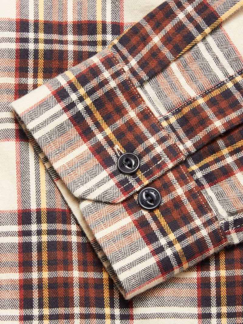 Close-up of the Blue de Gênes Robertino Brush Shirt - Stone: plaid flannel in beige, brown, orange, and black, with a buttoned cuff, herringbone weave, detailed stitching. Crafted in Portugal from premium Sidogras cotton.