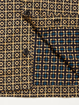 Close-up of the Blue de Gênes Manga Overshirt - Black Pattern. The cotton overshirt displays a yellow, blue, and black grid design with two black buttons and a folded flap revealing the reverse side and its modern workwear style.