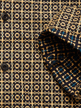 Close-up of the Blue de Gênes Manga Overshirt in a black pattern, showing black buttons and a geometric design with beige, blue, and black squares. The folded cuff highlights the distinctive grid motif.