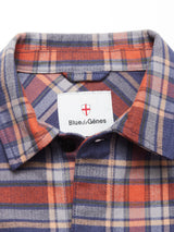 Close-up of the Yodo Check Overshirt - Multi Check by Blue de Gênes, featuring soft-touch moleskin in orange, blue, and cream plaid with a collar label displaying the brand name and a red shield emblem above.