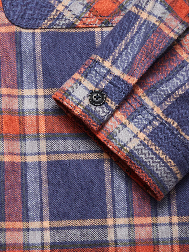 Close-up of the Blue de Gênes Yodo Check Overshirt - Multi Check, showing its relaxed fit, black buttoned cuff, visible stitching, and soft-touch moleskin in blue, orange, and cream plaid.