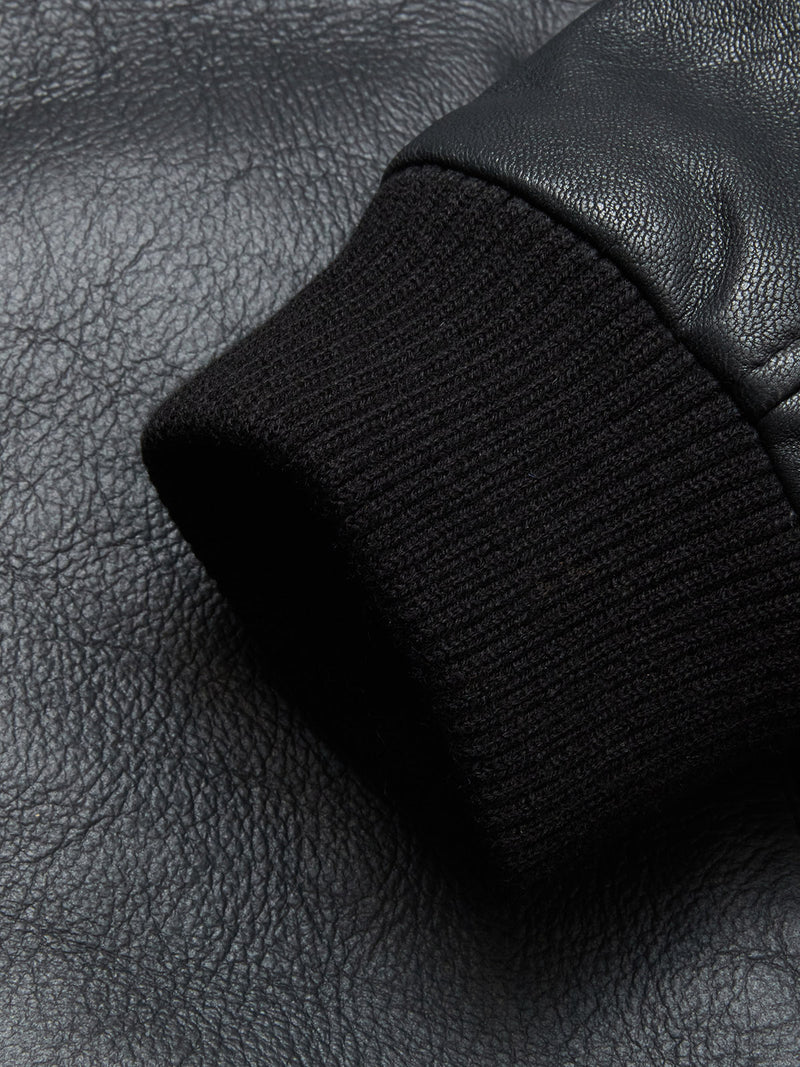 Close-up of a black ribbed cuff on the Rufo Shearling Jacket - Scarab by Blue de Gênes, showcasing detailed fabric and leather textures.